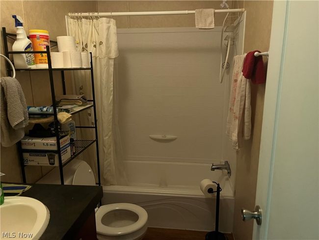 Full bathroom featuring sink, shower / bathtub combination with curtain, and toilet | Image 7