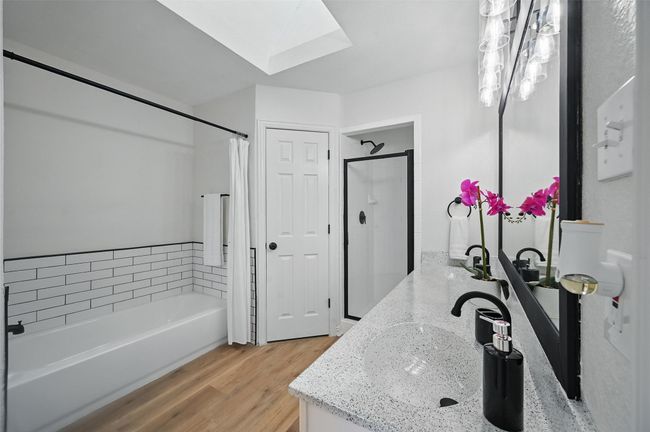 Full bathroom with a skylight, a tub to relax in, vanity, wood finished floors, and a​​‌​​​​‌​​‌‌​‌‌​​​‌‌​​‌‌​‌​​​​​‌ shower | Image 4