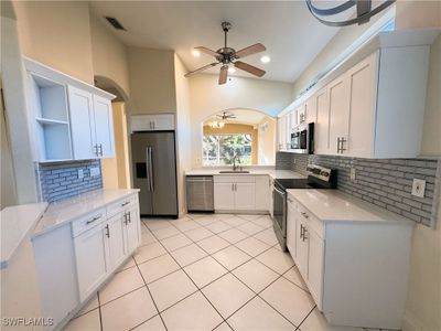 Kitchen with sink, appliances with stainless steel finishes, white cabinetry, and light tile patterned floors | Image 1