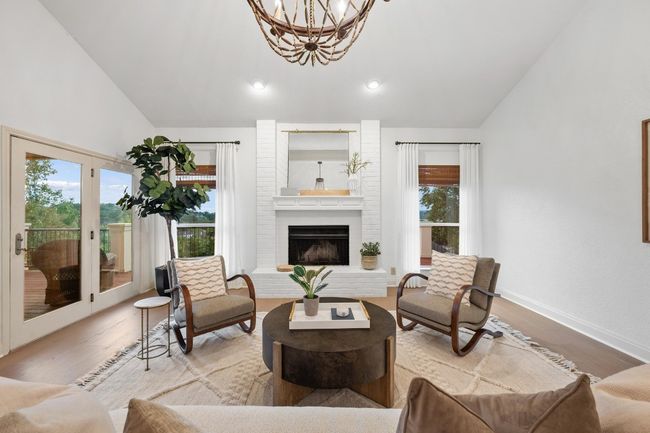 Living area featuring vaulted ceiling, wood finished floors, a chandelier, a brick fireplace, and recessed lighting | Image 7