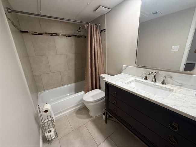 Bathroom with tile patterned floors, toilet, vanity, and shower / bathtub combination with curtain | Image 17