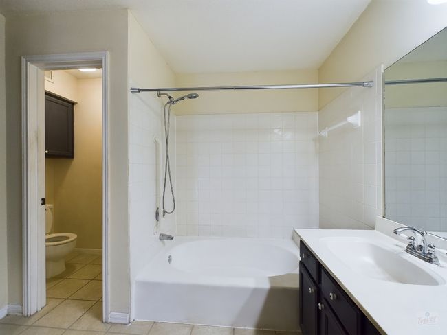 Full bathroom featuring tile patterned floors, toilet, shower / tub combination, vanity, and baseboards | Image 15