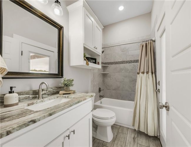 Bathroom featuring vanity, toilet, shower / bathtub combination with curtain, and wood finished floors | Image 23