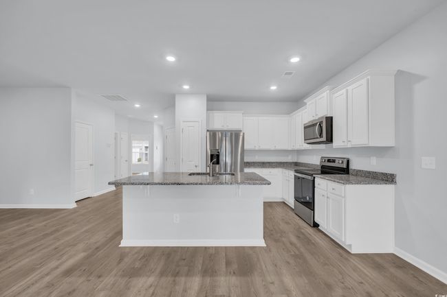 Kitchen featuring stainless steel appliances, visible vents, light wood-style flooring, and an island with sink | Image 5