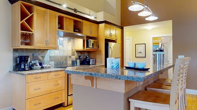 Kitchen featuring tasteful backsplash, under cabinet range hood, appliances with stainless steel finishes, and open shelves | Image 9
