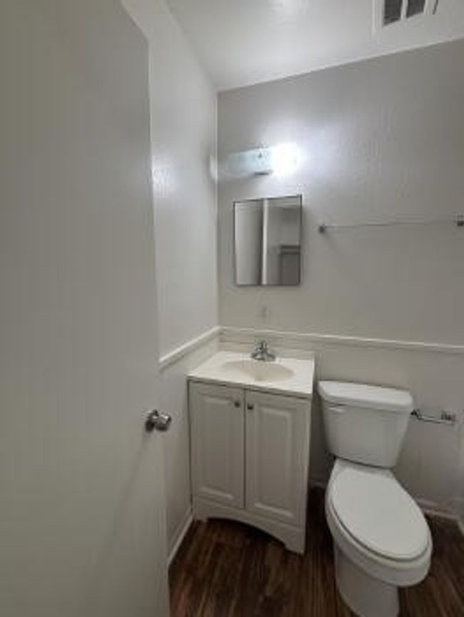 Bathroom featuring toilet, vanity, visible vents, and wood finished floors | Image 5