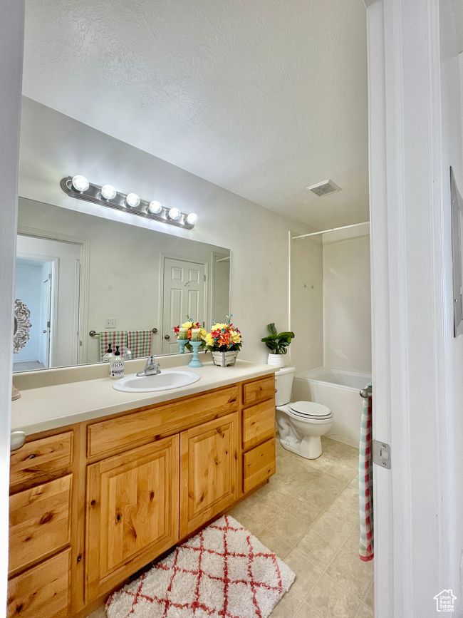 Bathroom featuring vanity, toilet, tile patterned floors, shower / bathtub combination, and a textured ceiling | Image 15