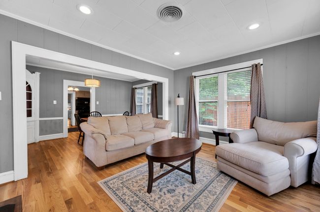 Living room with crown molding, light wood-style floors, a decorative wall, baseboards, and recessed lighting | Image 6