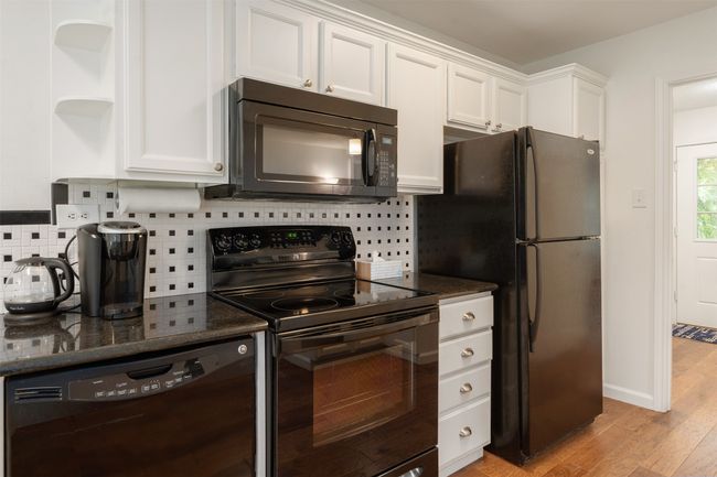 Kitchen featuring black appliances, white cabinetry, light wood-style flooring, open shelves, and tasteful backsplash | Image 16