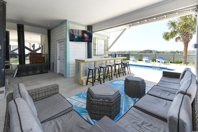 View of patio with fence, outdoor dry bar, a fenced in pool, and an outdoor living space | Image 27