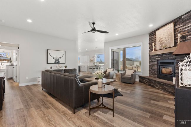 Living room with ceiling fan, wood finished floors, a fireplace, and recessed lighting | Image 9