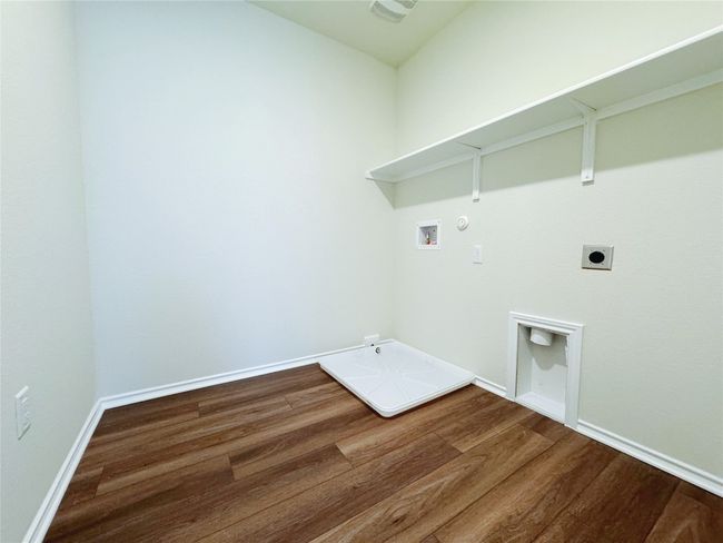 Laundry area with hookup for a gas dryer, washer hookup, electric dryer hookup, wood finished floors, and baseboards | Image 25