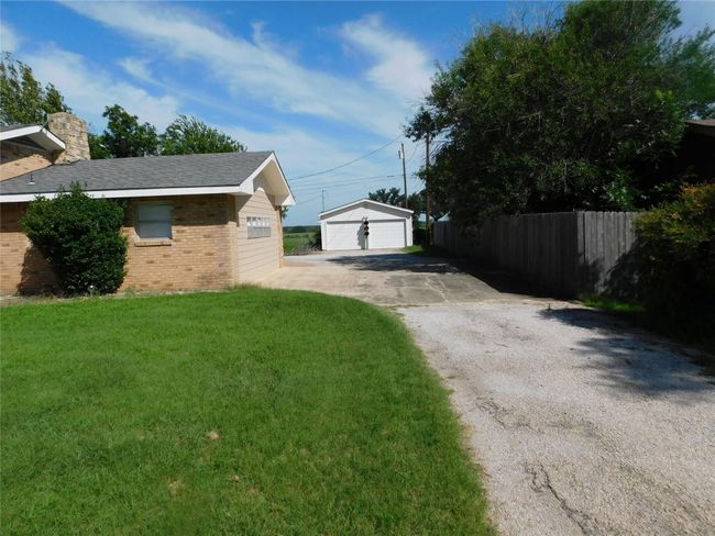View of side of home featuring brick siding, a garage, a chimney, and an outbuilding | Image 32