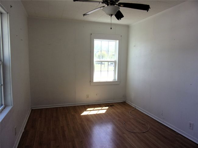 Unfurnished room featuring crown molding, ceiling fan, wood finished floors, and baseboards | Image 13
