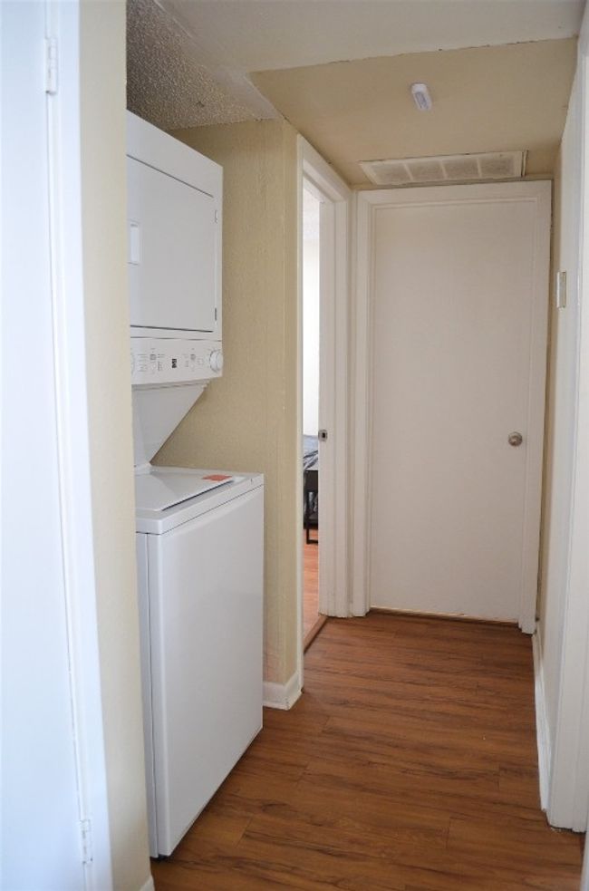 Washroom with stacked washer and clothes dryer and wood finished floors | Image 7