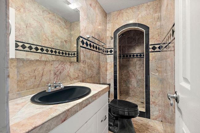 Bathroom featuring tile walls, a tile shower, toilet, vanity, and backsplash | Image 33