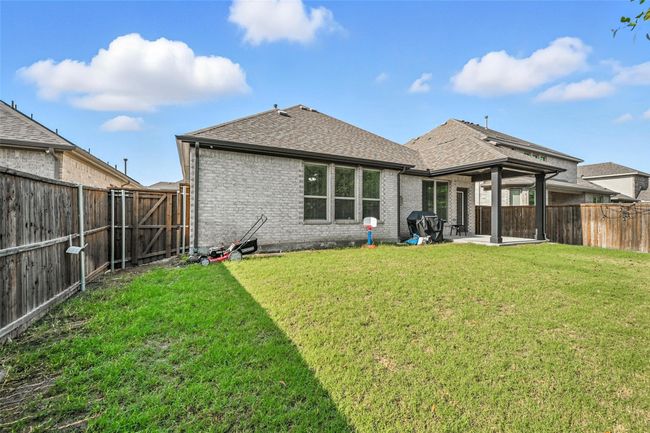 Rear view of house featuring a shingled roof, brick siding, a patio area, and a fenced backyard | Image 29