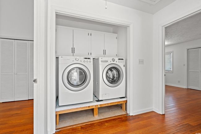 Washroom with hardwood / wood-style flooring and washing machine and clothes dryer | Image 27