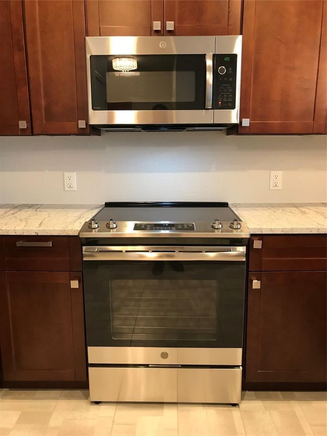 Kitchen featuring stainless steel appliances and light stone counters | Image 5