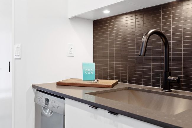 Detailed view of dishwasher, dark countertops, and white cabinets | Image 24