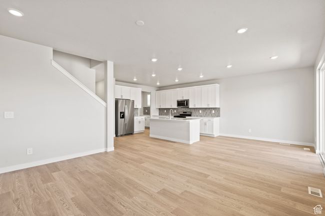 Unfurnished living room with recessed lighting, light wood-style flooring, baseboards, and stairs | Image 8