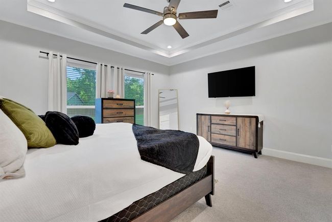 With soaring tray ceilings and gorgeous backyard views, the primary bedroom offers a relaxing retreat complete with a private en suite. | Image 25