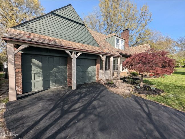 View of property exterior featuring an attached garage, a chimney, brick siding, and aphalt driveway | Image 14