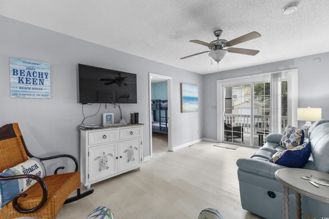 Living room featuring ceiling fan, light wood-style flooring, a textured ceiling, and baseboards | Image 6