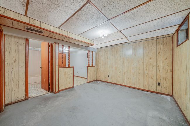 Finished below grade area with wood walls, baseboards, visible vents, and a drop ceiling | Image 22