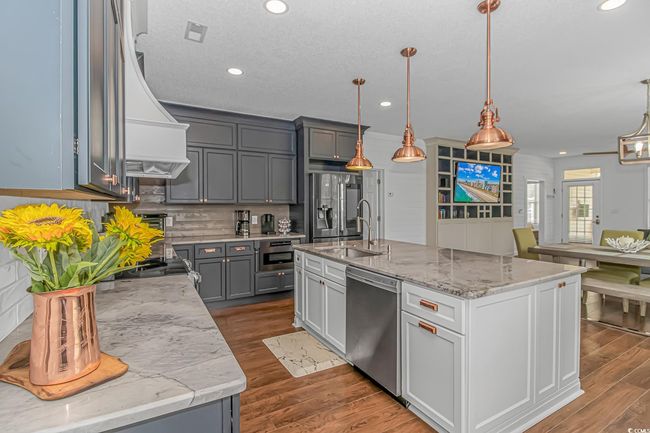 Kitchen featuring appliances with stainless steel finishes, a sink, wall chimney exhaust hood, tasteful backsplash, and wood finished floors | Image 13