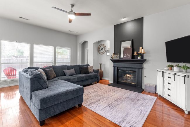 Living room with arched walkways, wood finished floors, visible vents, and a ceiling fan | Image 21