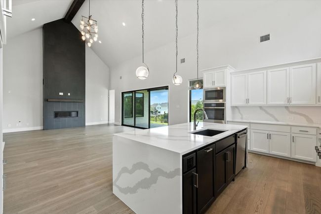 Kitchen featuring high vaulted ceiling, stainless steel appliances, beam ceiling, white cabinets, and hanging light fixtures | Image 17