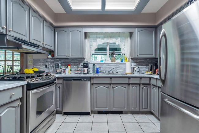Kitchen featuring gray cabinets, a sink, stainless steel appliances, light countertops, and under cabinet range hood | Image 9
