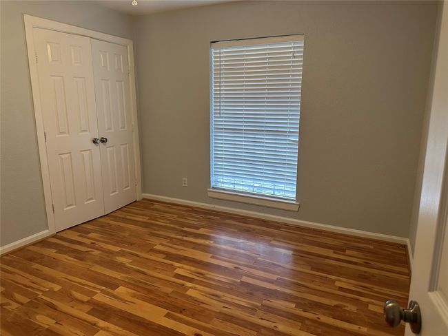 Unfurnished bedroom with baseboards, a closet, and wood finished floors | Image 7