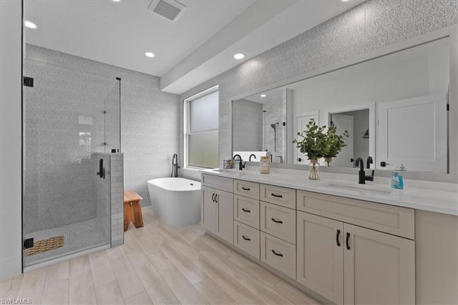 Bathroom featuring a stall shower, double vanity, a freestanding bath, wood finished floors, and recessed lighting | Image 24