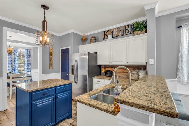 Kitchen featuring light stone countertops, hanging light fixtures, stainless steel fridge with ice dispenser, and blue cabinetry | Image 12