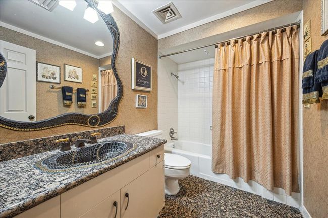 The secondary bathroom showcases a granite countertop, an elegant sink with a matching ornate mirror, and a classic tub/shower combination. | Image 23