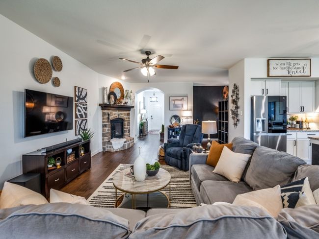 Living area with arched walkways, baseboards, a ceiling fan, a fireplace, and dark wood-type flooring | Image 7