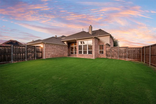 Back of property at dusk featuring brick siding, a fenced backyard, and a chimney | Image 31