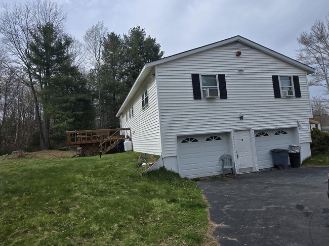 View of side of property with a lawn, aphalt driveway, a wooden deck, and an attached garage | Image 4