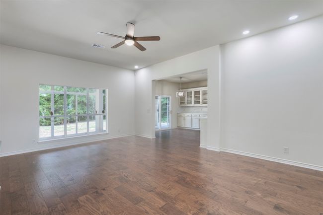Unfurnished living room featuring a ceiling fan, dark wood-style floors, baseboards, and recessed lighting | Image 7
