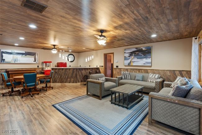 Living room with a wainscoted wall, wooden ceiling, wood finished floors, and visible vents | Image 41