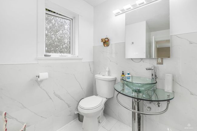 Bathroom featuring tile walls, a sink, toilet, and a wainscoted wall | Image 19