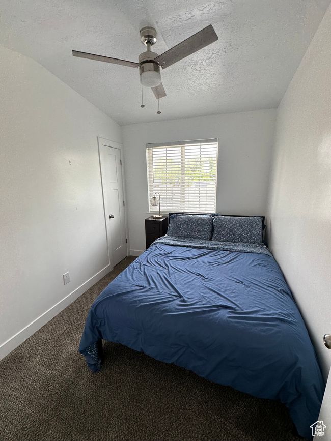 Carpeted bedroom with a textured ceiling, baseboards, and a ceiling fan | Image 12