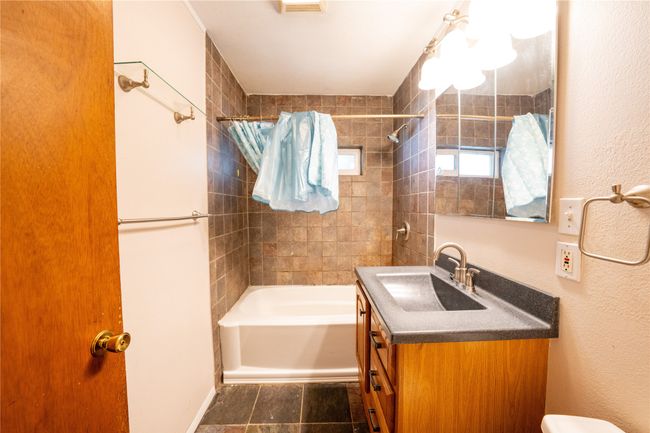 Full bath featuring vanity, bathing tub / shower combination, toilet, and a textured wall | Image 20