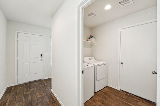 Clothes washing area featuring laundry area, separate washer and dryer, visible vents, and dark wood-style flooring | Image 11