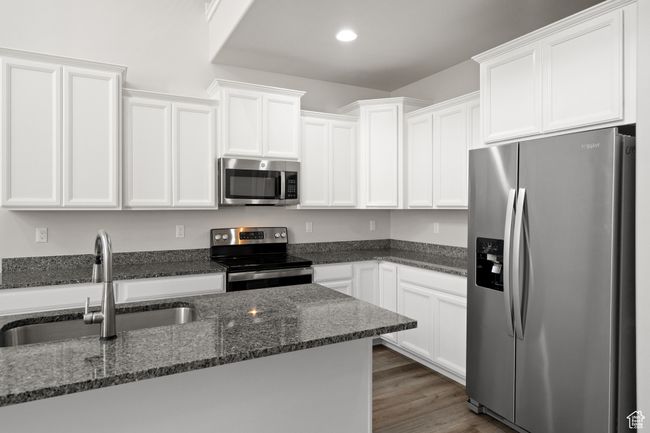 Kitchen featuring stainless steel appliances, white cabinets, dark stone countertops, and recessed lighting | Image 14