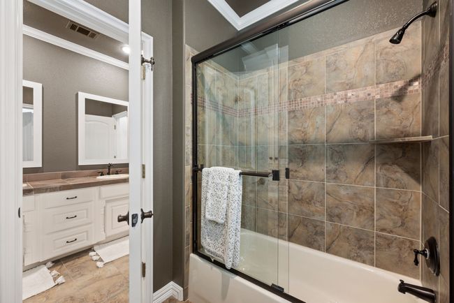 Full bathroom with an enclosed tub / shower combo, dual vanity, and tiled floors. | Image 28