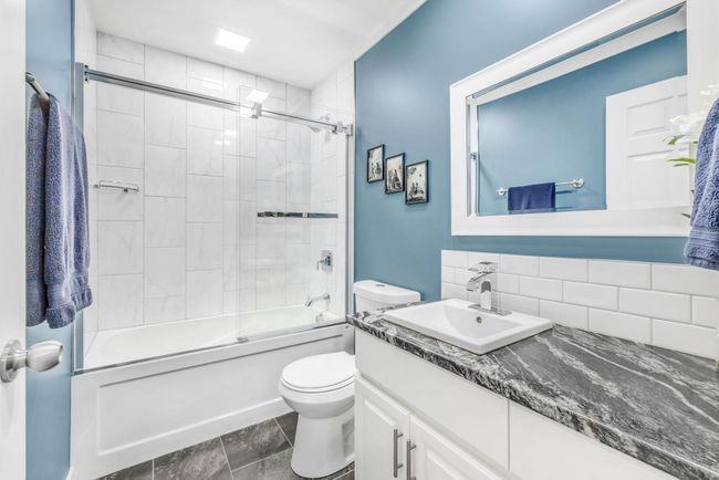 Full bath featuring toilet, combined bath / shower with glass door, vanity, and backsplash | Image 16