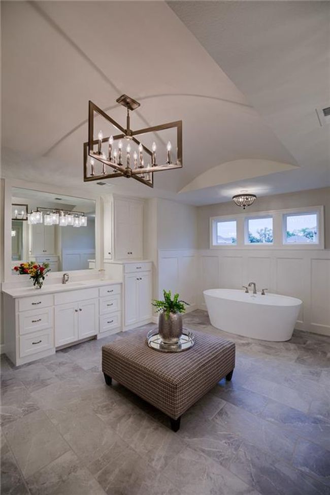 Bathroom with an inviting chandelier, tile flooring, vanity, and a bath | Image 33